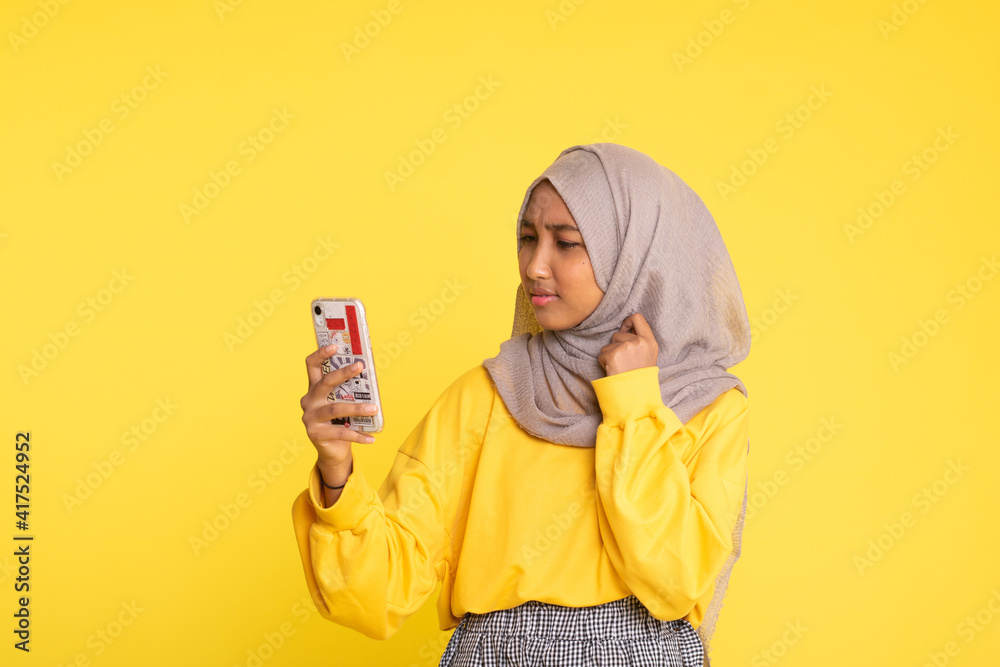 Woman playing mobile game isolated over yellow background. Woman playing mobile game isolated over yellow background.
