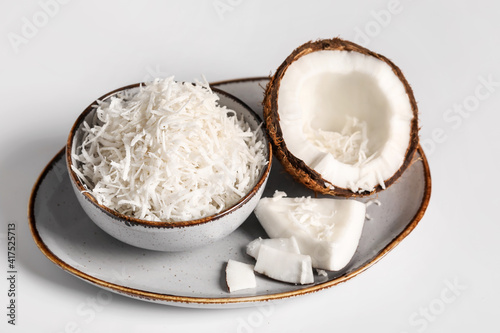 Plate with coconut flakes on white background