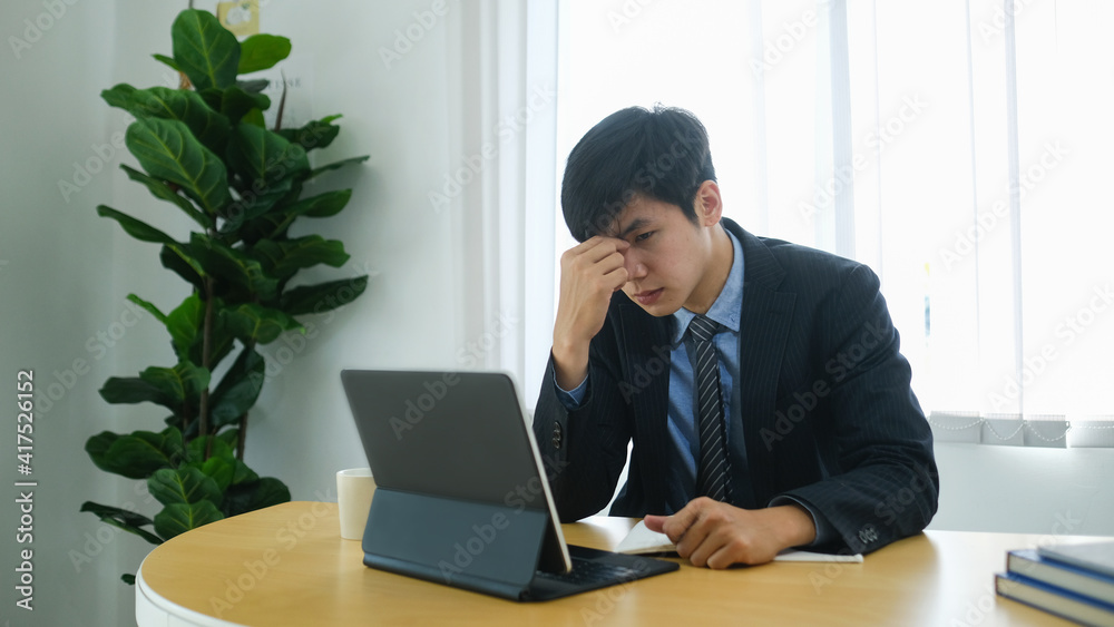 Exhausted businessman feeling tired and suffering from eye strain after long computer tablet use. Exhausted businessman feeling tired and suffering from eye strain after long computer tablet use.