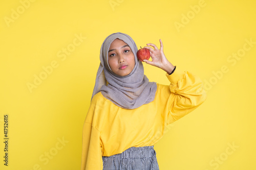 beautiful girl with red apple on yellow background © faishalabdula