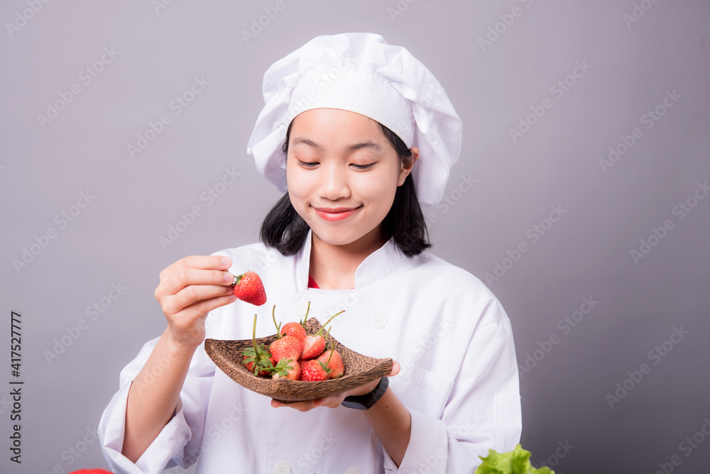 Portrait of a young Asian female chef ready to cook a new dish in the kitchen. Contains Strawberry as an ingredient Portrait of a young Asian female chef ready to cook a new dish in the kitchen. Contains Strawberry as an ingredient