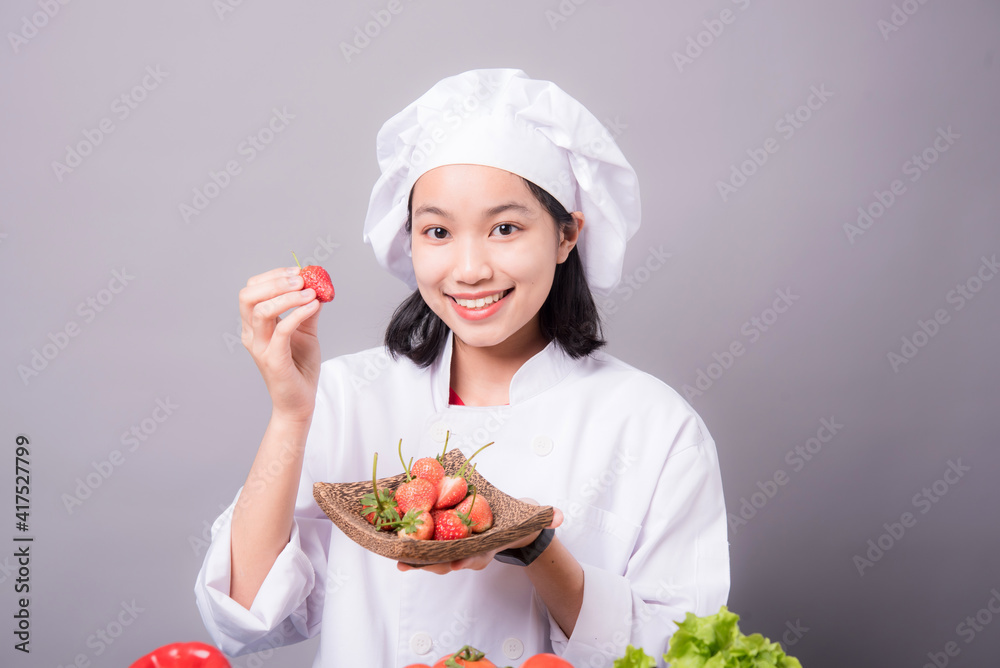 Portrait of a young Asian female chef ready to cook a new dish in the kitchen. Contains Strawberry as an ingredient Portrait of a young Asian female chef ready to cook a new dish in the kitchen. Contains Strawberry as an ingredient
