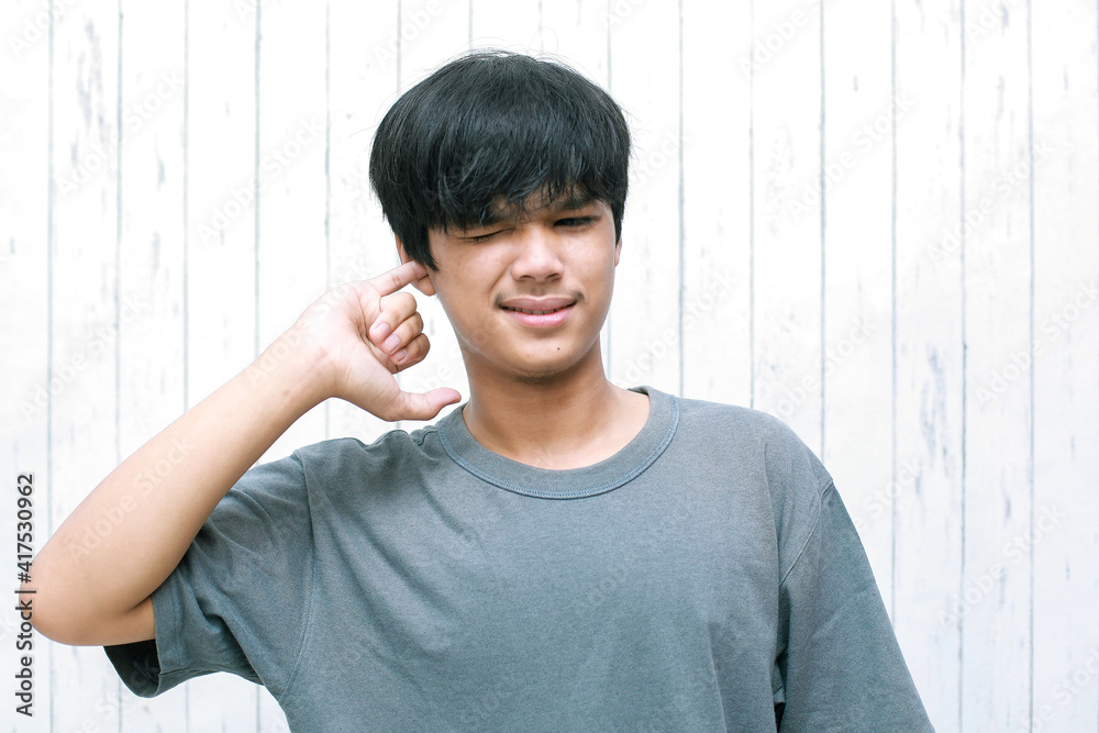 Young asian man picking his ear with his finger. Feeling itchy in the ears