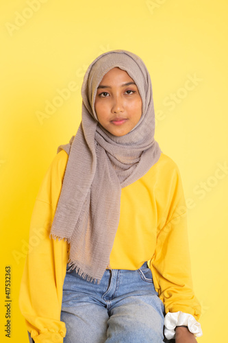 Fashion portrait of young beautiful asian muslim woman with wearing hijab isolated on yellow background. © faishalabdula