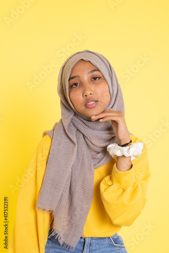 Fashion portrait of young beautiful asian muslim woman with wearing hijab isolated on yellow background.