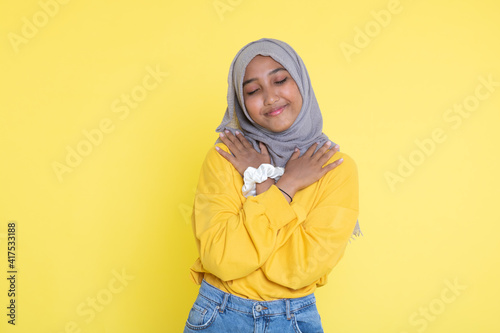 Fashion portrait of young beautiful asian muslim woman with wearing hijab isolated on yellow background. © faishalabdula