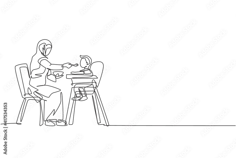 Single continuous line drawing of young Islamic mother feeding organic food to her toddler boy at home. Arabian muslim happy family motherhood concept. Trendy one line draw design vector illustration