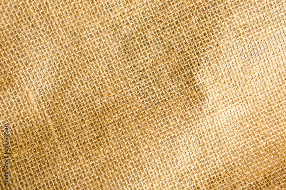 The texture of burlap, rough weave in a cage made of natural fiber, yellow-brown color. Copyspace, close-up The texture of burlap, rough weave in a cage made of natural fiber, yellow-brown color. Copyspace, close-up