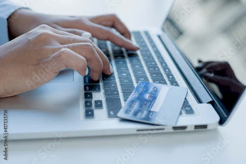 The businesswoman's hand is holding a credit card and using a laptop for online shopping and internet payment