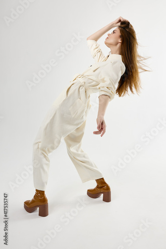 stylish woman in white jumpsuit fashion leaned back holding her hair
