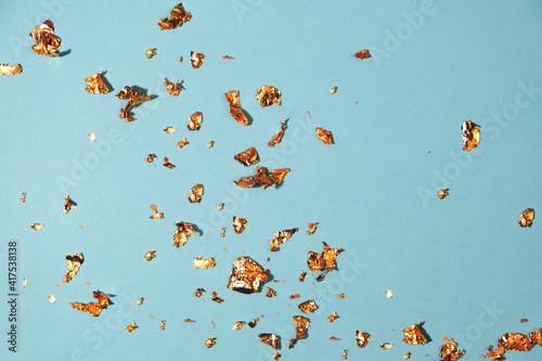 Blue background with pieces of gold leaf. Background for your design or lettering. Close-up.