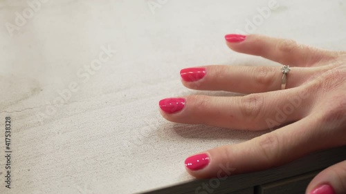 a young European girl paints her nails with pink nail polish