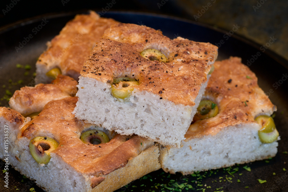 Pieces of fresh soft moist sourdough focaccia with green olives