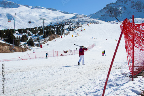 A skier walking with her skis on her shoulders.nobody's face is visible.ski track.winter sport.