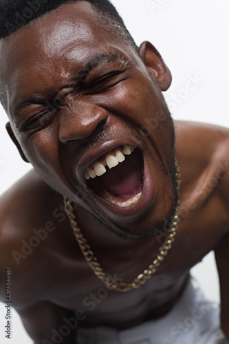 Emotional portrait of an African man on white background. Black guy model screams with closed eyes