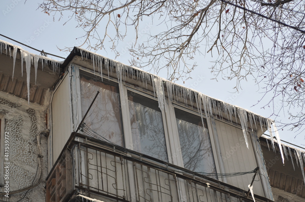Naklejka premium Icicles hang from the roof of the balcony