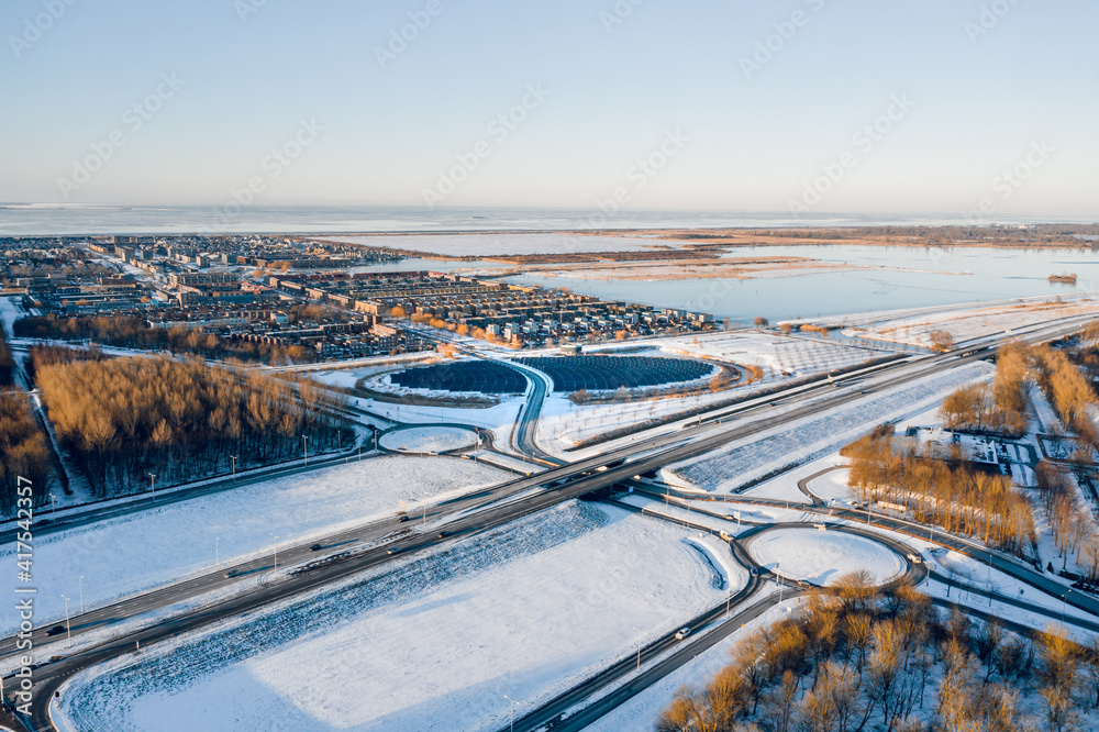 Modern sustainable neighbourhood surrounded by nature in Almere, The Netherlands, powered by solar energy. Winter landscape. Aerial shot.