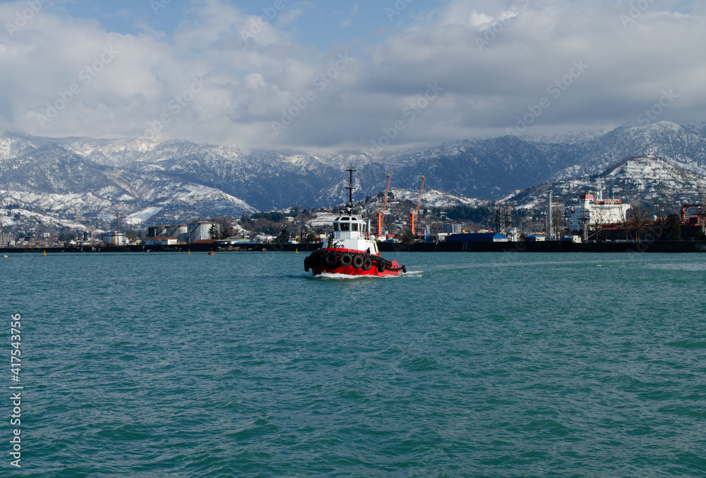 Boat in the Black Sea, against the backdrop of snowy mountains. Off the coast of the resort town of Batumi, Georgia.