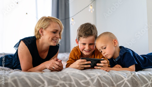 Happy family mother and children playing with digital devices at home