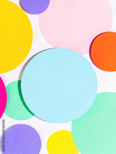 Background of colorful paper circles in memphis geometric style. Cut out circles styled layout with hard light and shadows. Vivid abstract background or template.