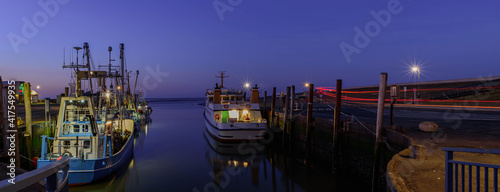 View of port Strucklahnungshörn at Nordstrand peninsula with ships at night,North Sea, North Frisia,Germany.  photo