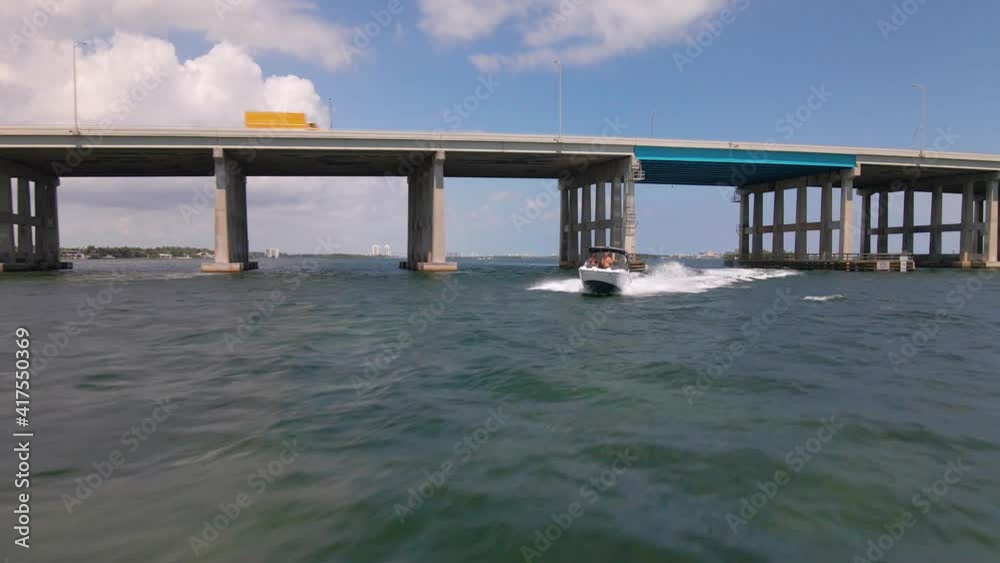 Aerial view over a boat, driving away from the William M Powell Bridge, in Miami - reverse, drone shot Aerial view over a boat, driving away from the William M Powell Bridge, in Miami - reverse, drone shot