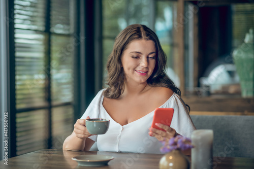 Young woman with coffee and smartphone