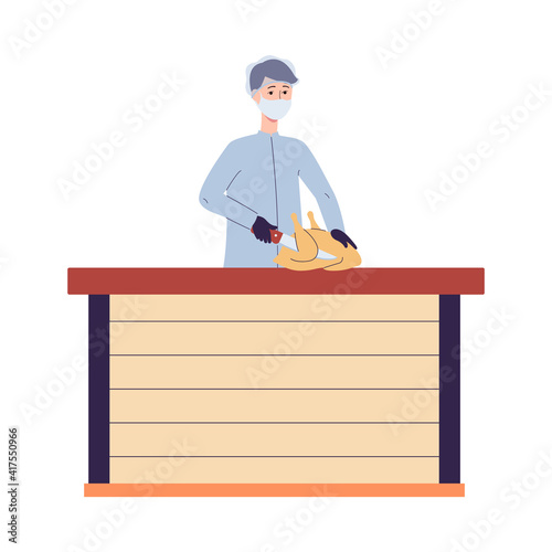 Male worker of chicken factory cuts the chicken carcass into pieces.
