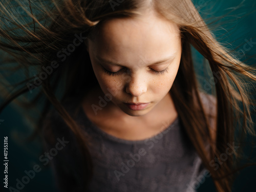 Portrait of a beautiful girl with closed eyes on a turquoise background and loose hair close-up cropped view.