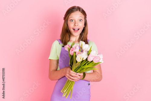 Photo portrait of small girl keeping tulip flowers bunch amazed staring opened mouth isolated on pastel pink color background