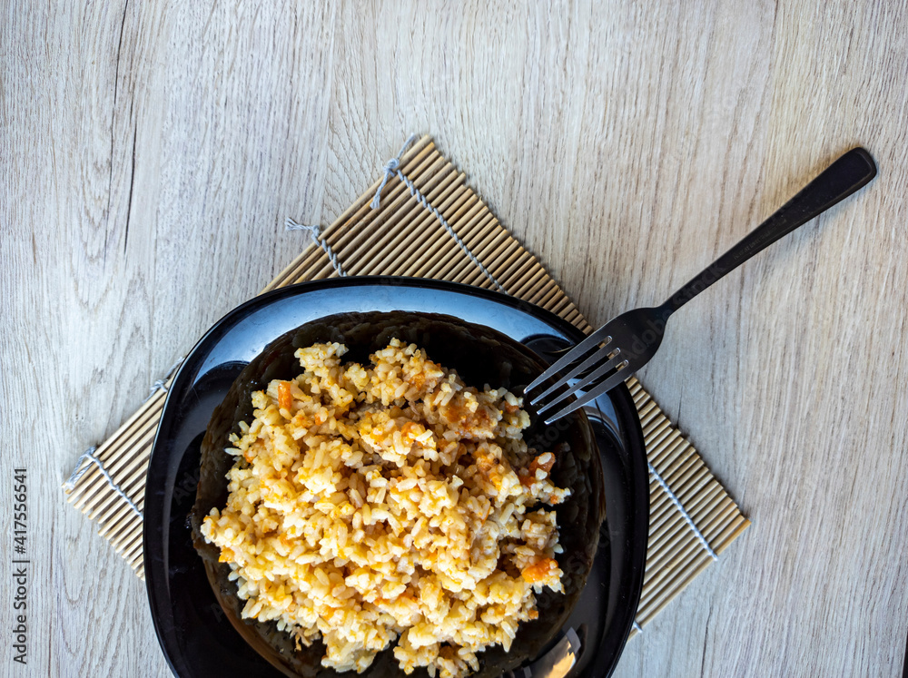 photo of pilaf in a black plate on a white background. rice dish. photo of food. View from above.