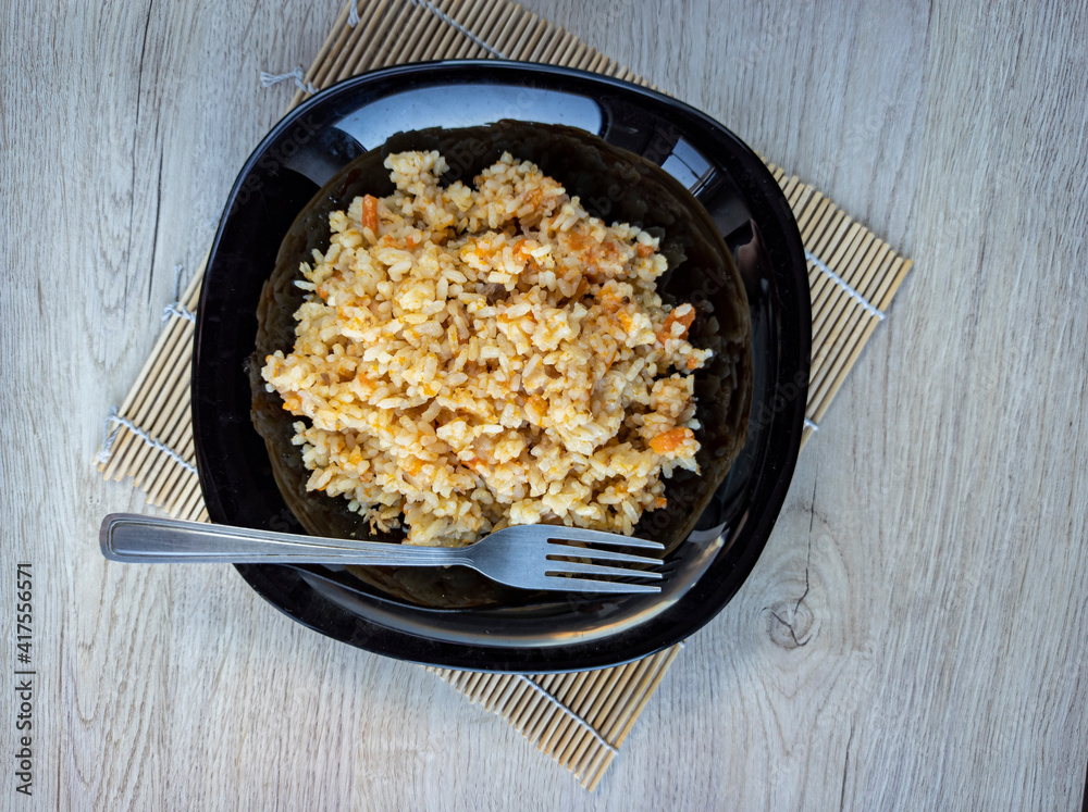 photo of pilaf in a black plate on a white background. rice dish. photo of food. View from above.