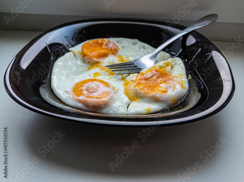 Obraz na płótnie photo of fried eggs in a black plate on a white background. food photo w salonie