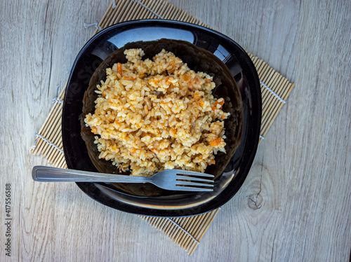 Obraz na płótnie photo of pilaf in a black plate on a white background. rice dish. photo of food. View from above. w salonie
