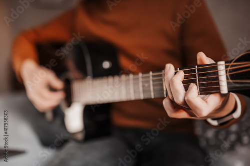 Man learning to play guitar with the help of online learning at home