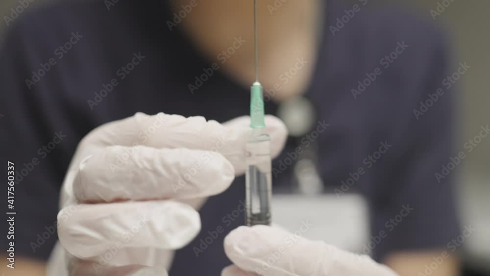 Doctor Tapping Syringe Of Clear Liquid Doctor Tapping Syringe Of Clear Liquid
