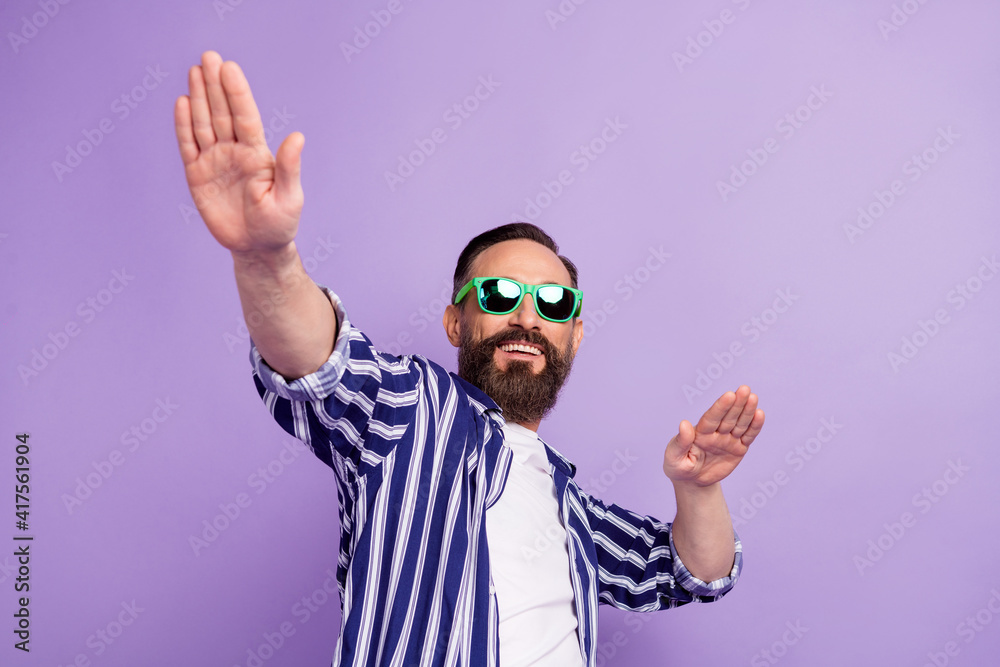 Photo of positive mature man in sunglass hold hands dance isolated over purple color background Photo of positive mature man in sunglass hold hands dance isolated over purple color background