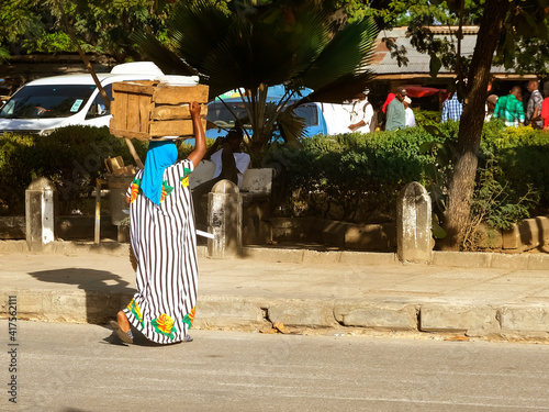 African or Indian woman carries wooden box on head. Zanzibar, Tanzania, Africa