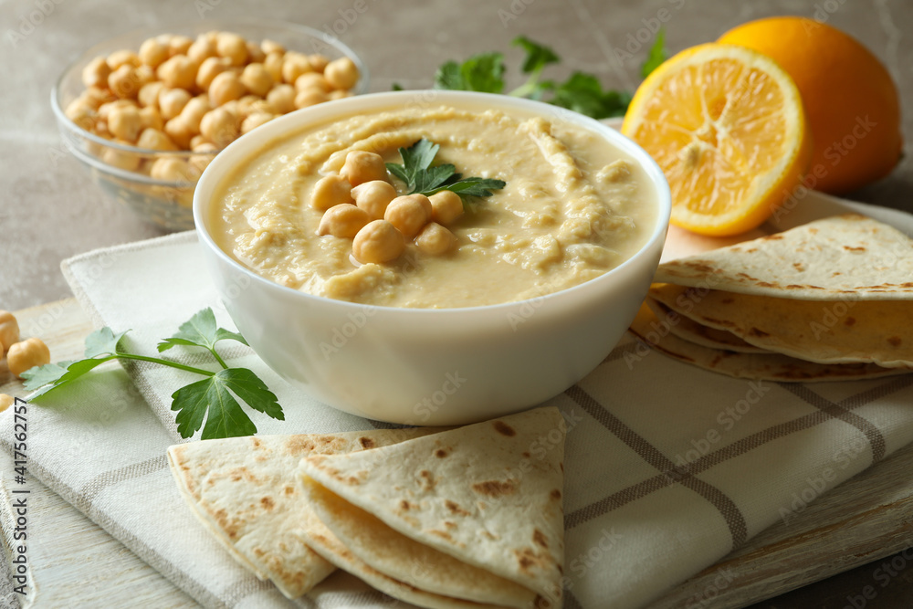 Concept of tasty eat with bowl of hummus on gray background Concept of tasty eat with bowl of hummus on gray background