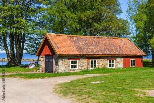 Old red idyllic shed with people having picnic