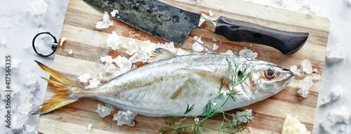 Uncooked horse mackerel on cutting board with knife photo