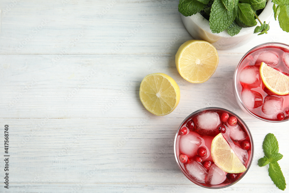 Tasty refreshing cranberry cocktails with lemon on white wooden table, flat lay. Space for text Tasty refreshing cranberry cocktails with lemon on white wooden table, flat lay. Space for text