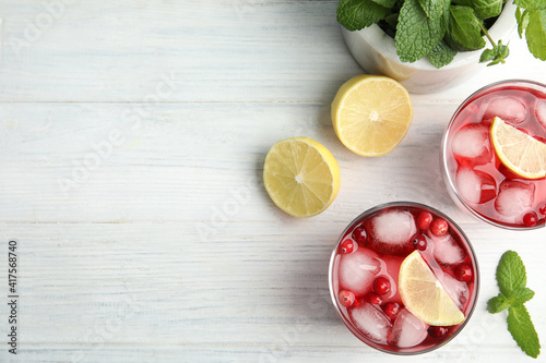 Tasty refreshing cranberry cocktails with lemon on white wooden table, flat lay. Space for text