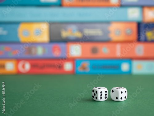 Two dice on the background of board game boxes. Dice games for kids, tweens and adults