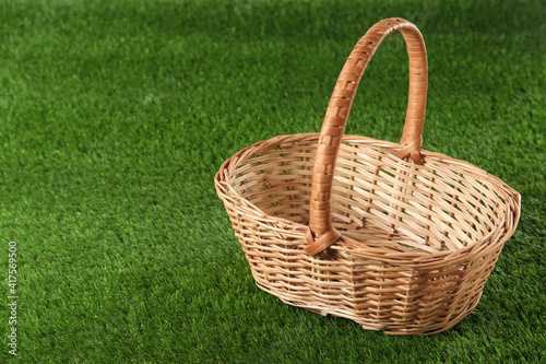 Empty wicker basket on green lawn  space for text. Easter item