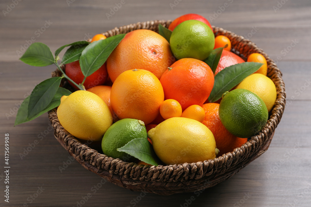 Different citrus fruits in basket on wooden table Different citrus fruits in basket on wooden table