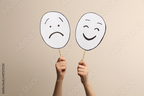 Foto Woman with sad and happy paper faces on beige background, closeup