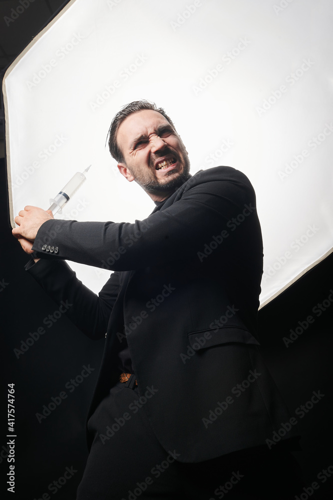 A vaccination of happy. Scientist business man in black suit with syringe in hand welcoming vaccine shot. Medical concept. A vaccination of happy. Scientist business man in black suit with syringe in hand welcoming vaccine shot. Medical concept.