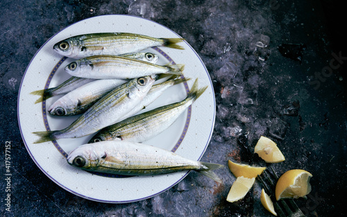 Raw fish on plate near fresh lemon slices photo