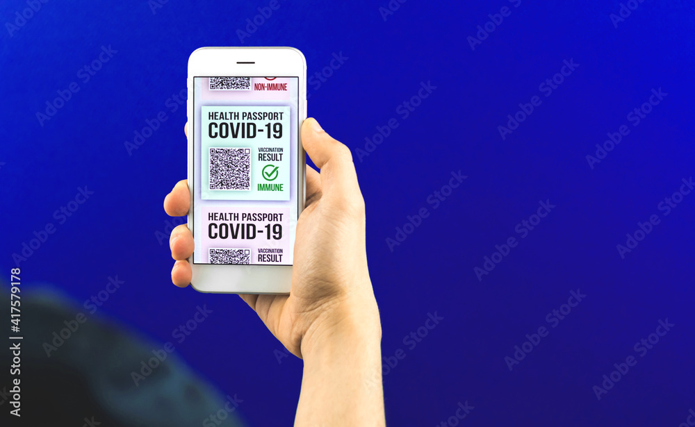 Vaccinated young man holds mobile phone with health passport application, concept for new normal and safe travels during COVID-19 pandemic Vaccinated young man holds mobile phone with health passport application, concept for new normal and safe travels during COVID-19 pandemic